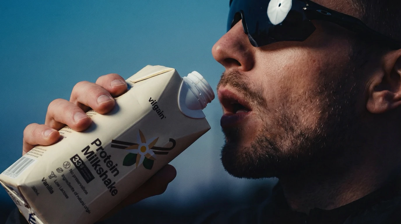 Man in sunglasses drinking Vilgain Protein Milkshake outdoors